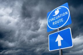 A Directional Sign in Front of Storm Clouds indicating the Storm Evacuation Route. A Directional Sign in Front of Storm Clouds indicating the Storm Evacuation Route.
