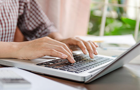 Una persona escribiendo en un escritorio en una computadora portátil