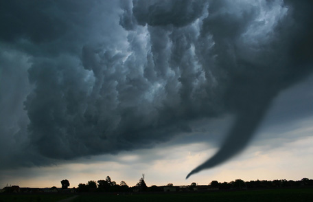 Cómo mantenerse seguro durante un tornado Cielos muy oscuros y una nube de embudo que toca el suelo.