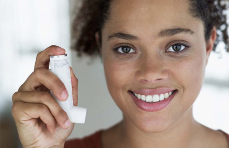 Una mujer joven sonriente que sostiene un inhalador