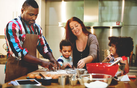 No coma masa cruda Padres y sus hijos haciendo galletas en la cocina.