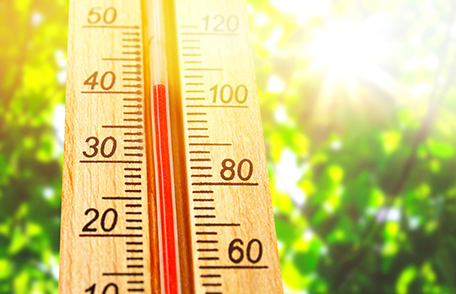 Termómetro que muestra aproximadamente 100 grados Fahrenheit con un soleado cielo azul como fondo