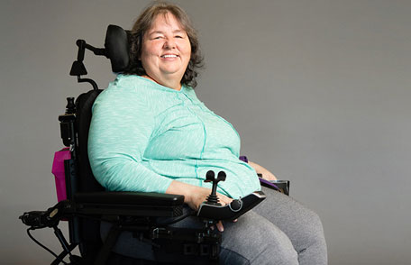 Paciente con esclerosis lateral amiotrófica (ELA) en silla de ruedas sonriendo. Paciente con esclerosis lateral amiotrófica (ELA) en silla de ruedas sonriendo.