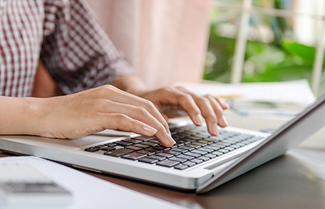 A person typing on a laptop keyboard.