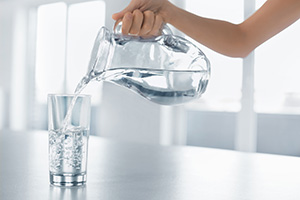 Drink Water. Woman's Hand Pouring Water From Pitcher Into Glass