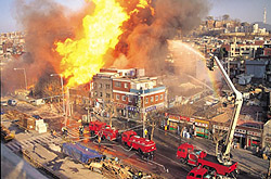 Fire City Aerial view of a building in a city on fire with firetrucks putting out the fire.