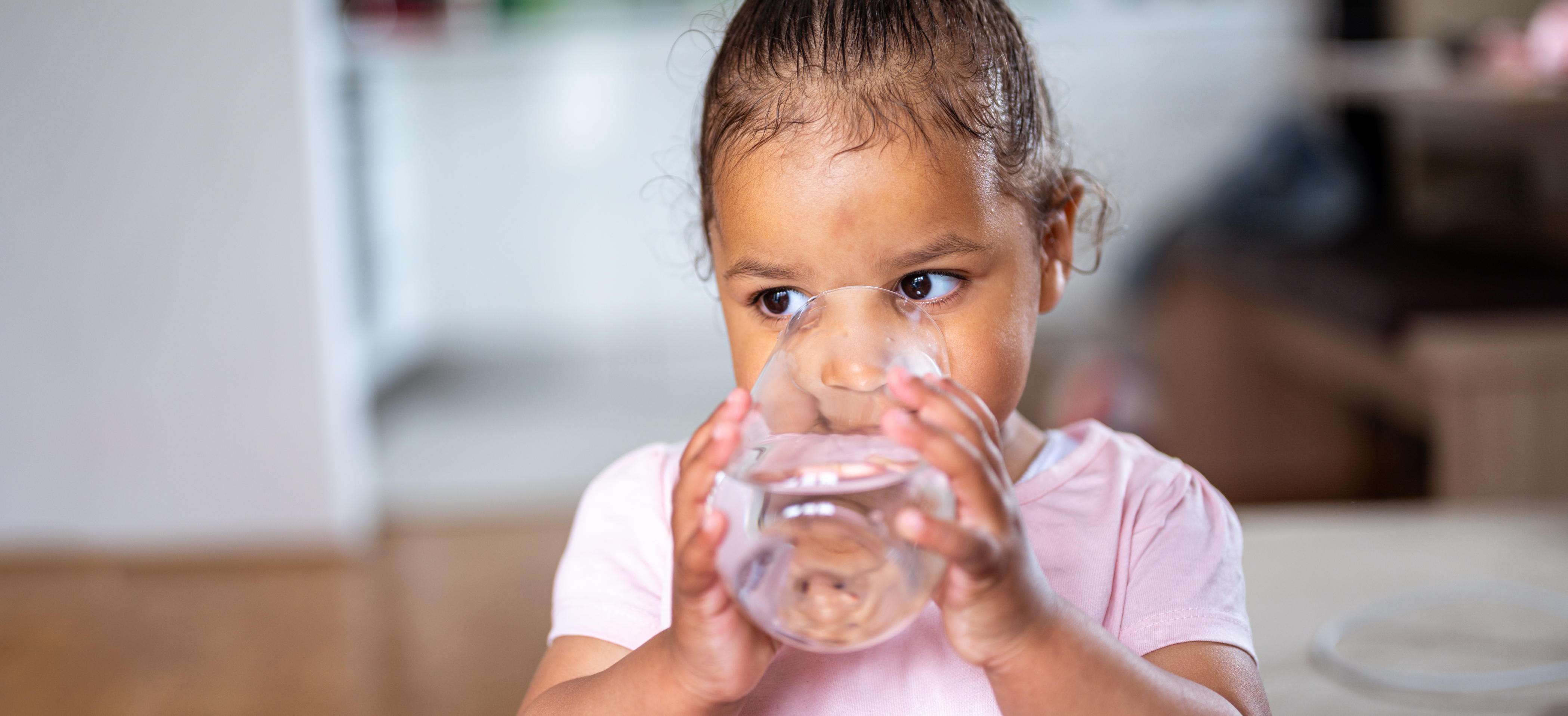ATSDR PFAS A small child with a pink shirt drinking water out of a glass.