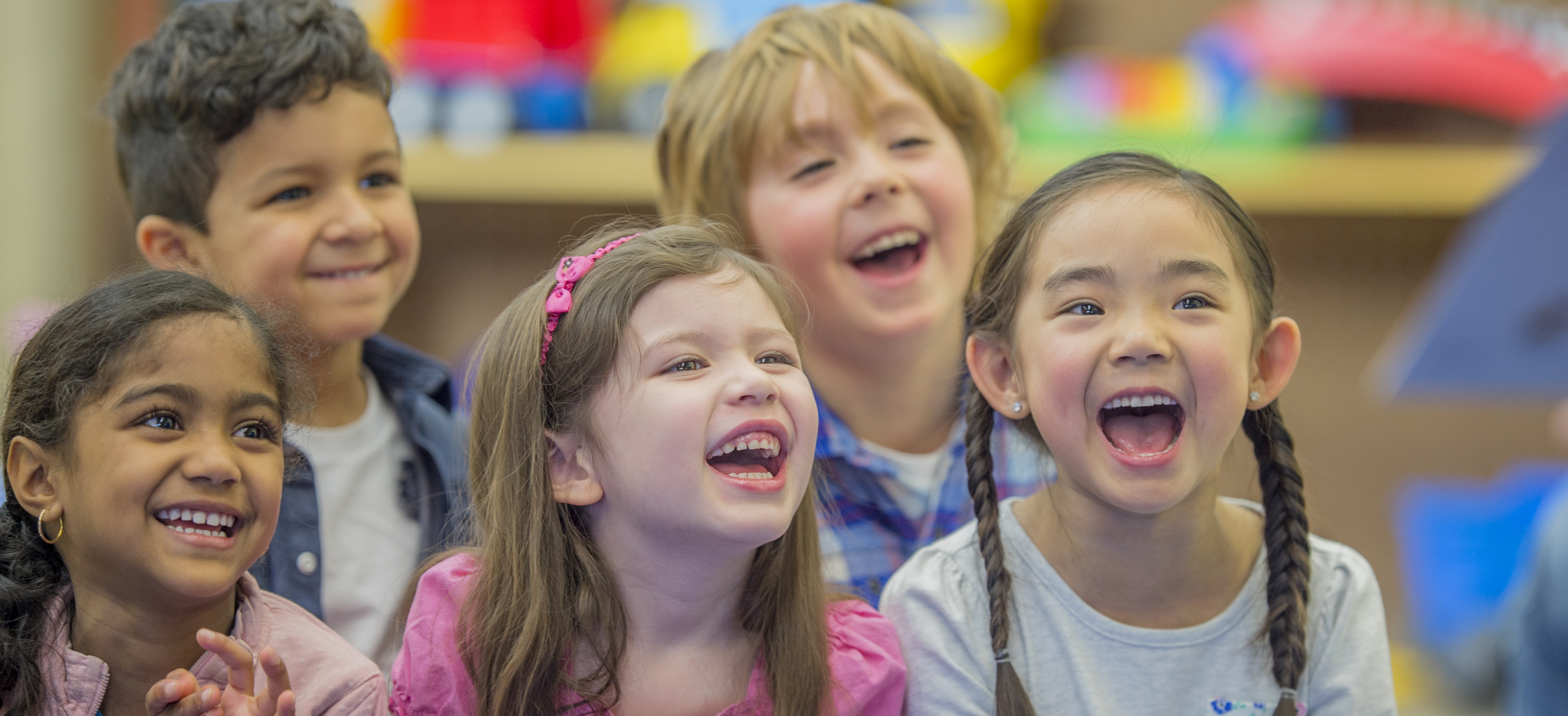 Choose Safe Places A group of five children laughing with brightly colored toys behind them.