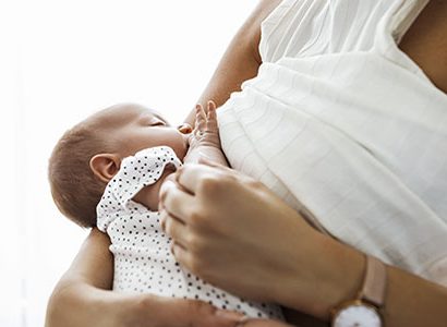 Mother breastfeeding and holding newborn baby