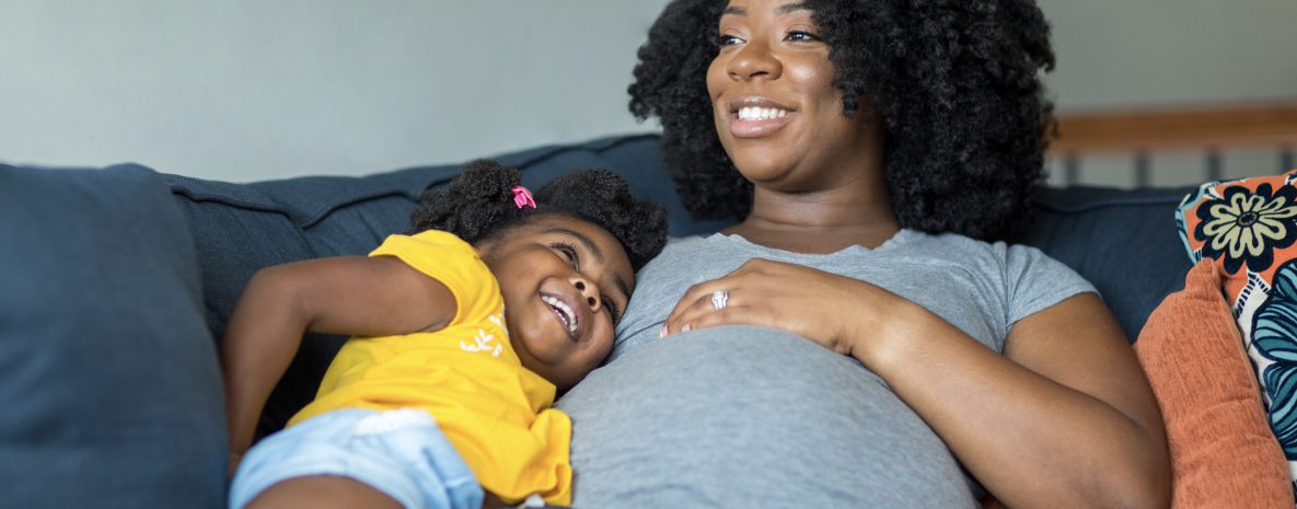 Mamá afroamericana embarazada y su hija.