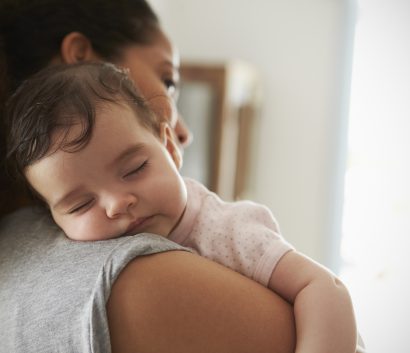 Imagen de cerca de una mamá cargando a su bebita dormida