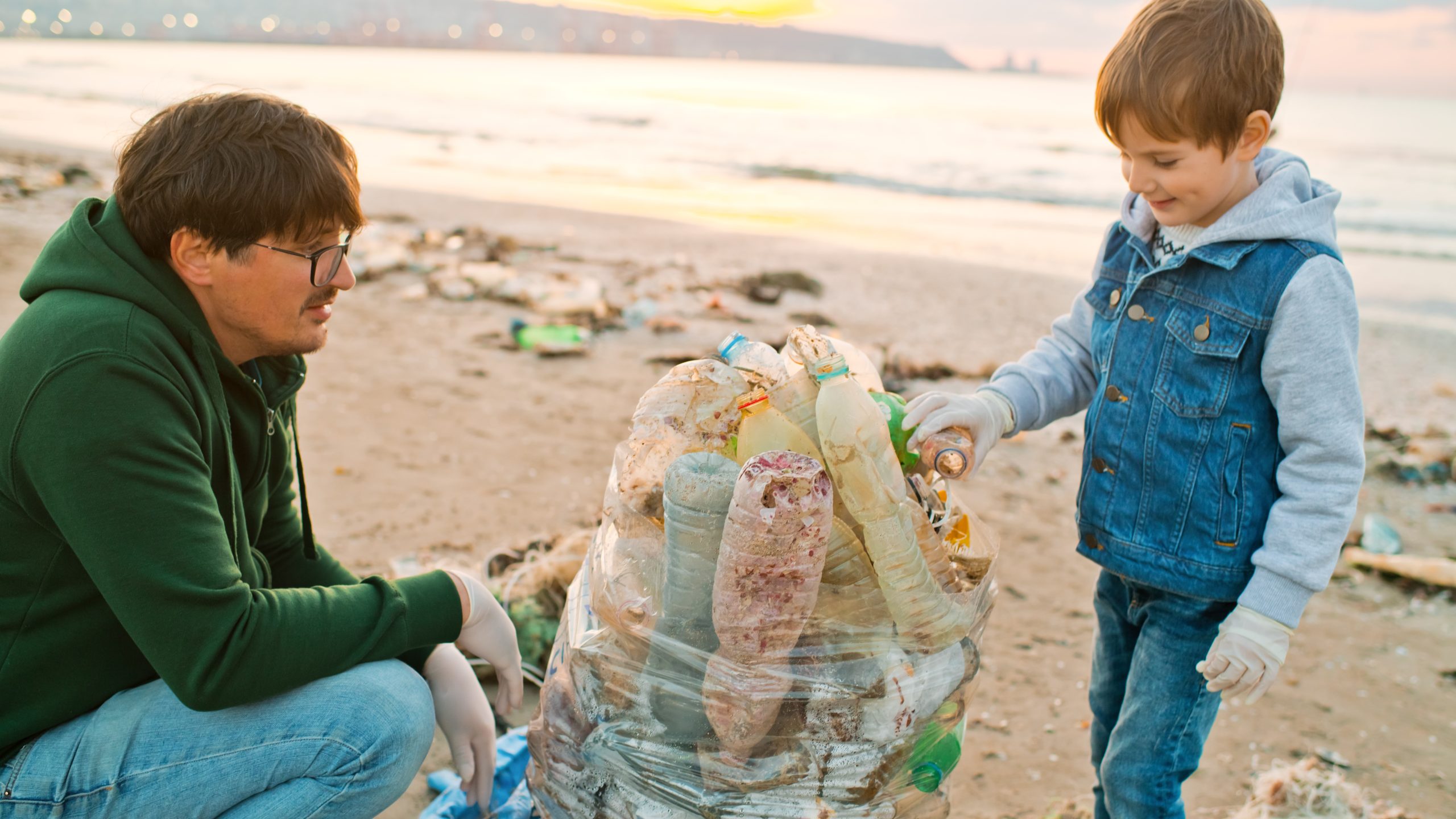 Father and son collecting plastic trash on a beach