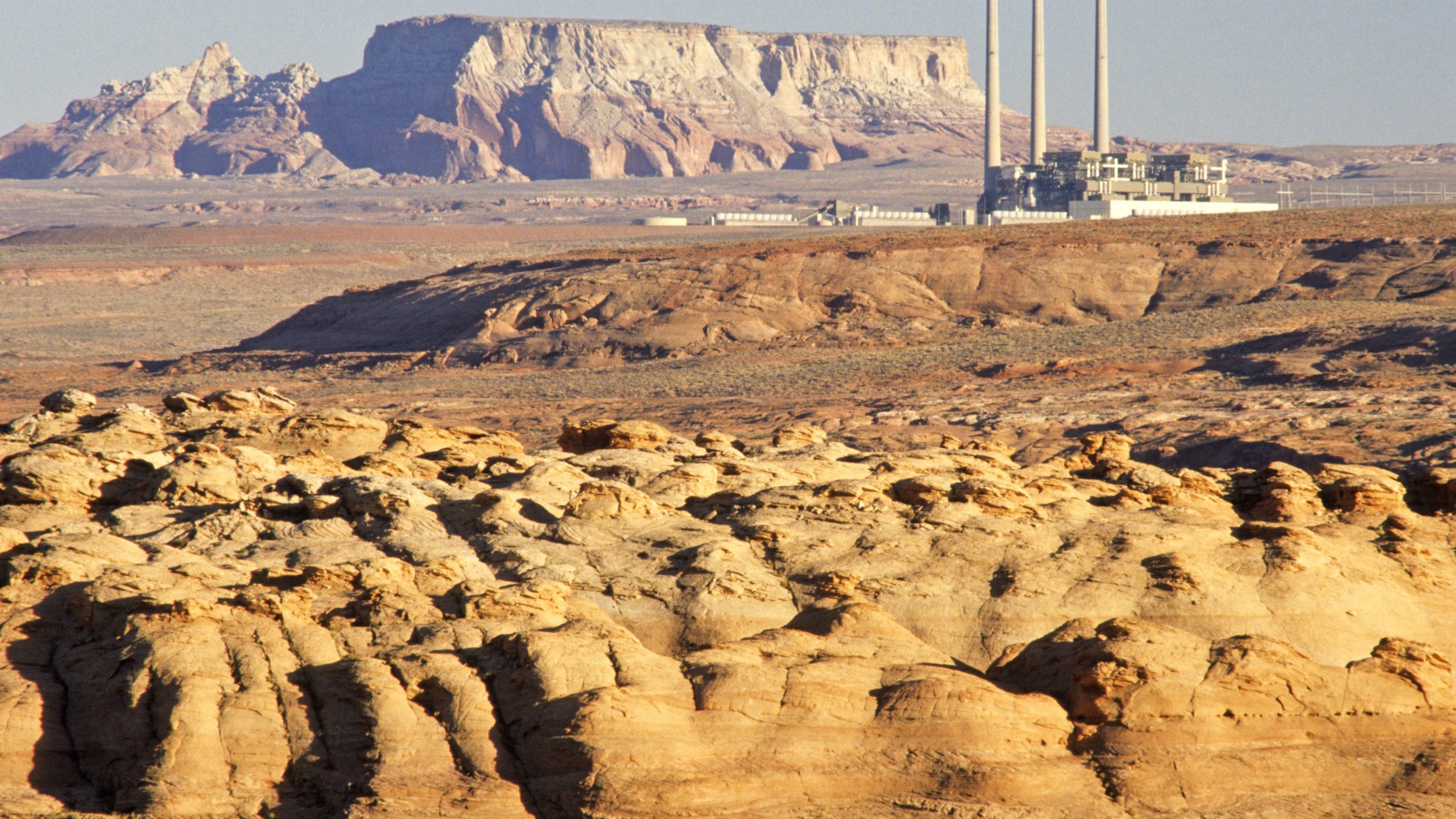 Desert with a power plant at a distance in the background.