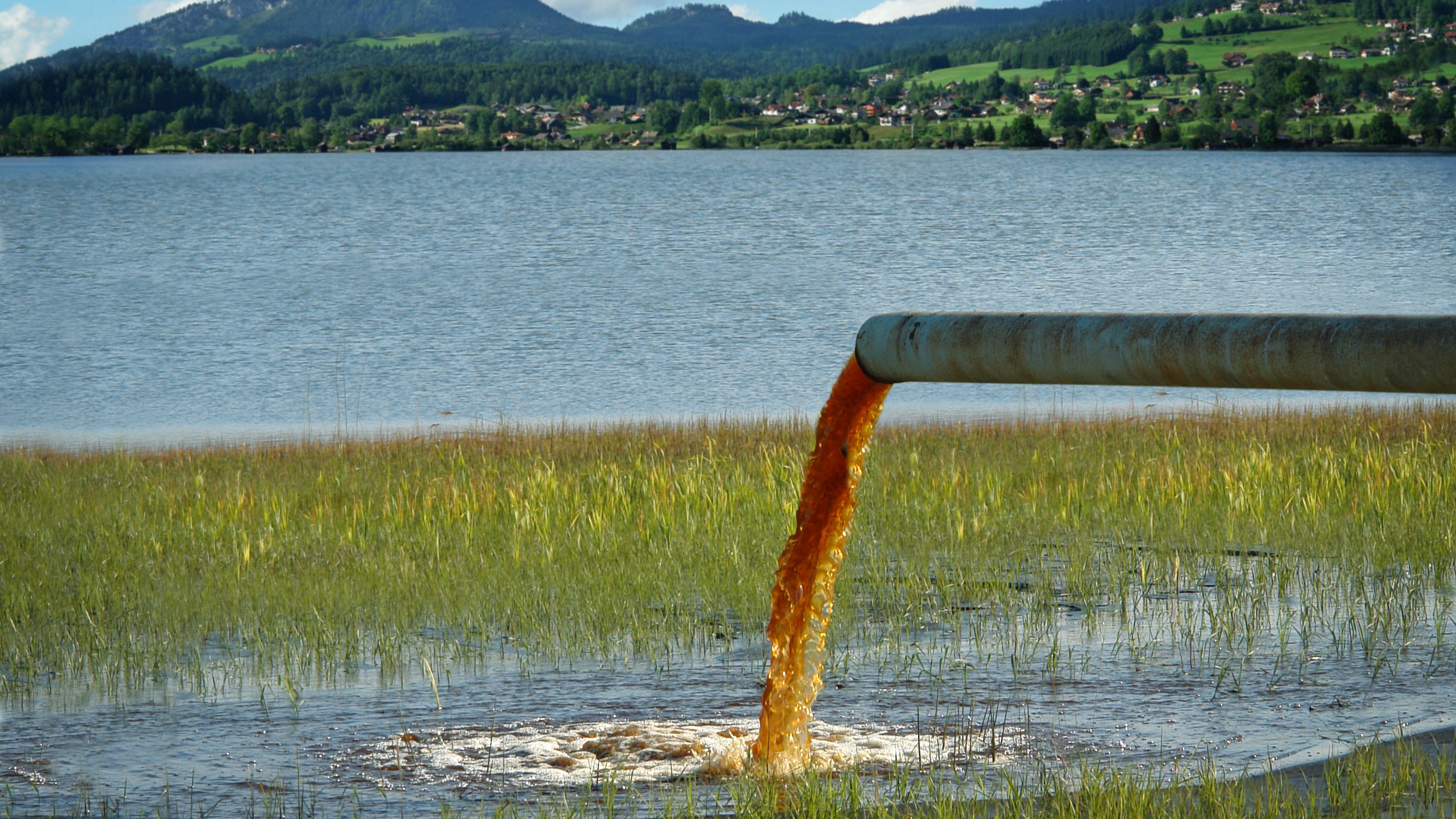 Dirty water flowing from a pipe into a lake