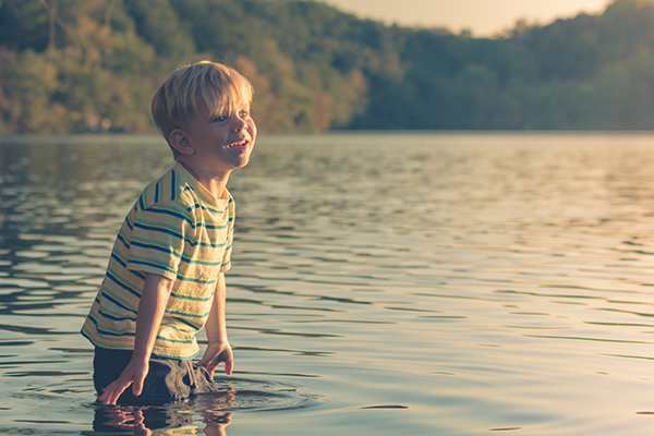 Young boy standing in a lake and smiling