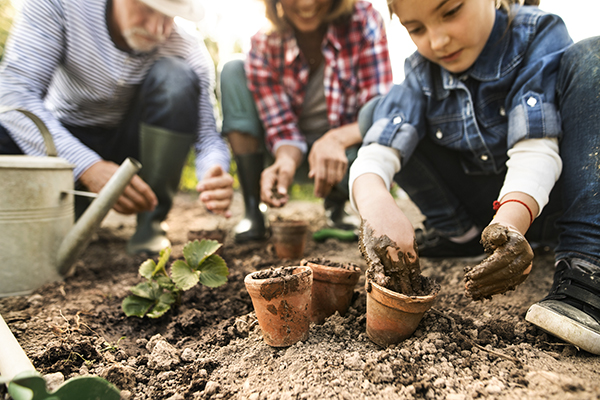 Two adults and a child gardening and putting plants in pots