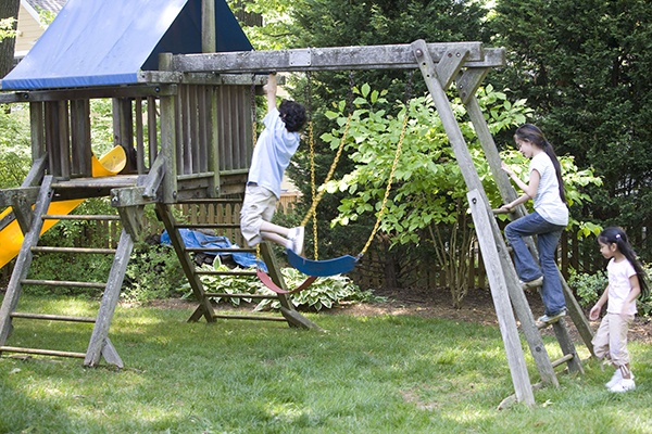 Three children play on a treehouse outside