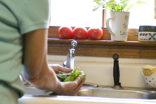 Person washing produce in the sink