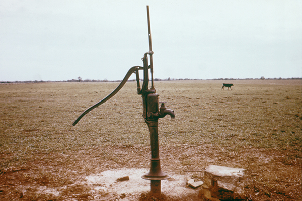 A water pump in a field full of brown dirt