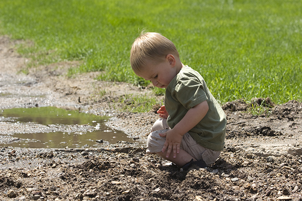 Toddler playing in mud after rainfall on park trail
