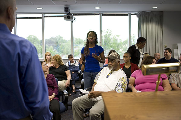 Community Meeting Guidelines A woman in a blue shirt addresses a crowd of people at a meeting