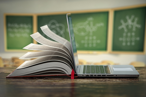 Laptop and open book sitting on desk