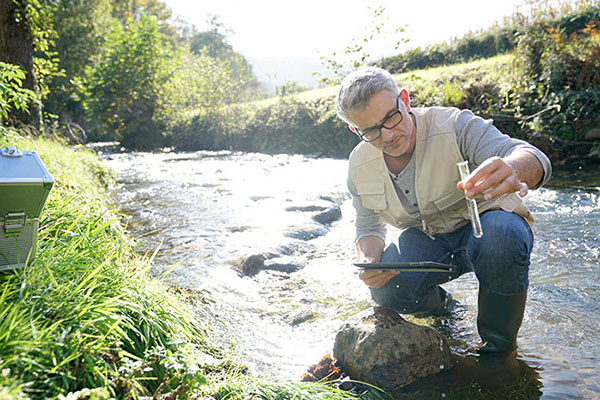 Biologist squatting in a river taking a water sample