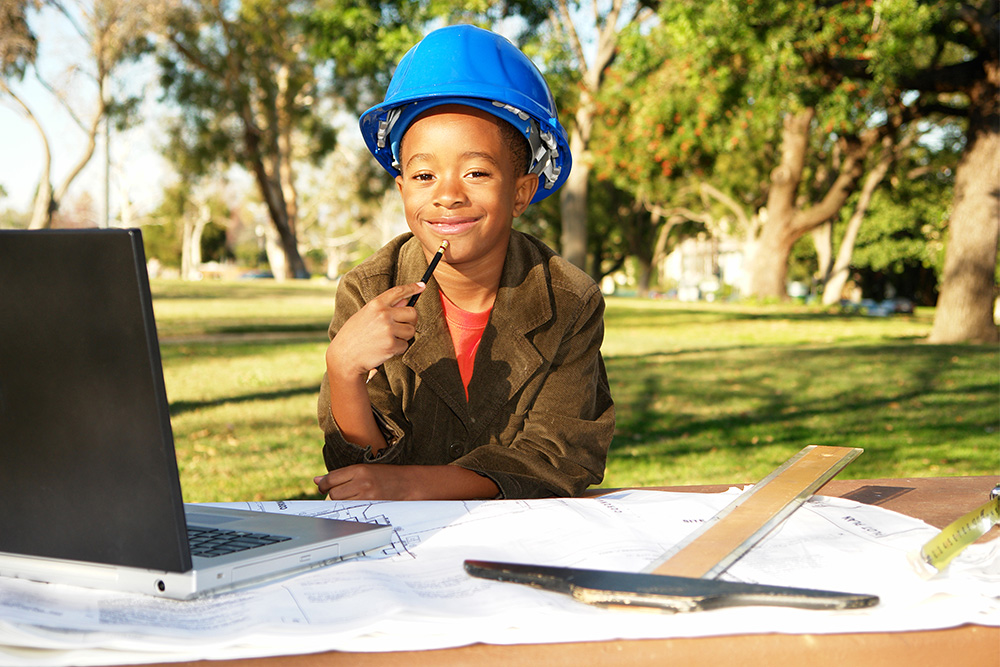 A young boy pretending to be a builder outdoors.