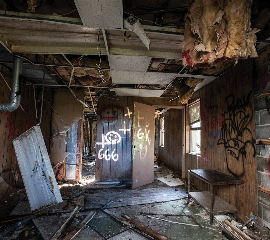 A vacant building filled with debris and spray painted symbols.